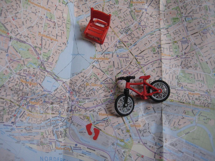 Foto Rundgang Hamburg: Miniatur-Fahrrad, -Klappstuhl, -Fuspuren auf Stadtplan. Fotografin: Maren Cornils